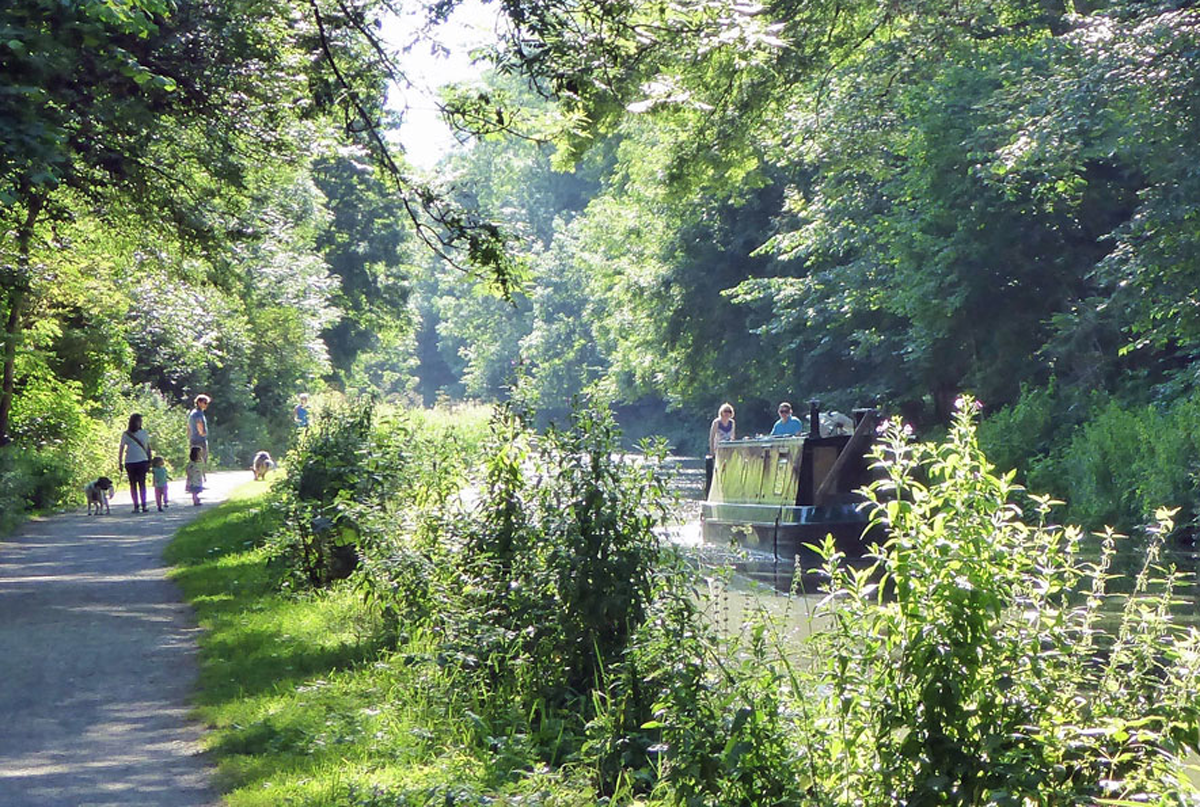 Family walking alongside canal, with green trees above and around