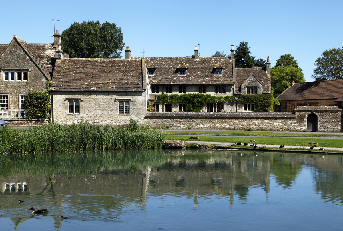 Traditional houses made of cotswold stone next to a village pond