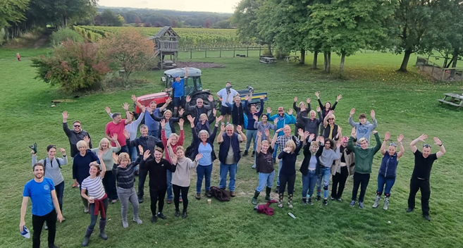 large group of people in the vineyard waving