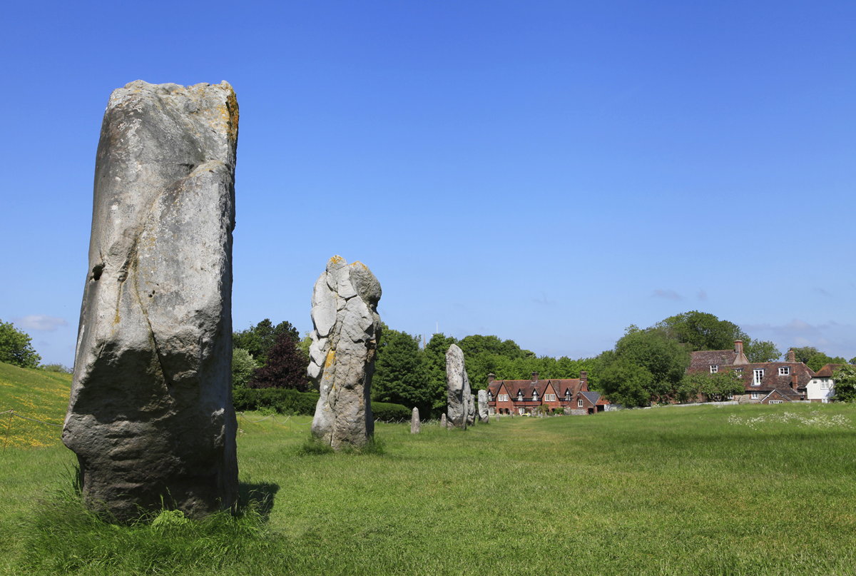 Standing stones with houses behind and blue sky