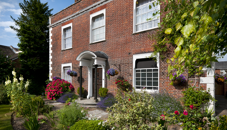 red brick townhouse with garden full of flowers