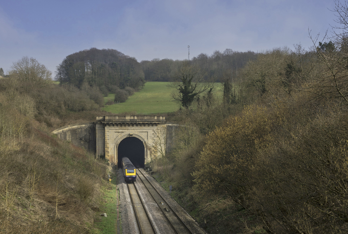 train emerging from hillside tunnel