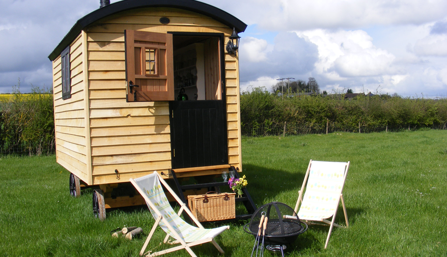 wooden shepherds hut with deck chairs in front
