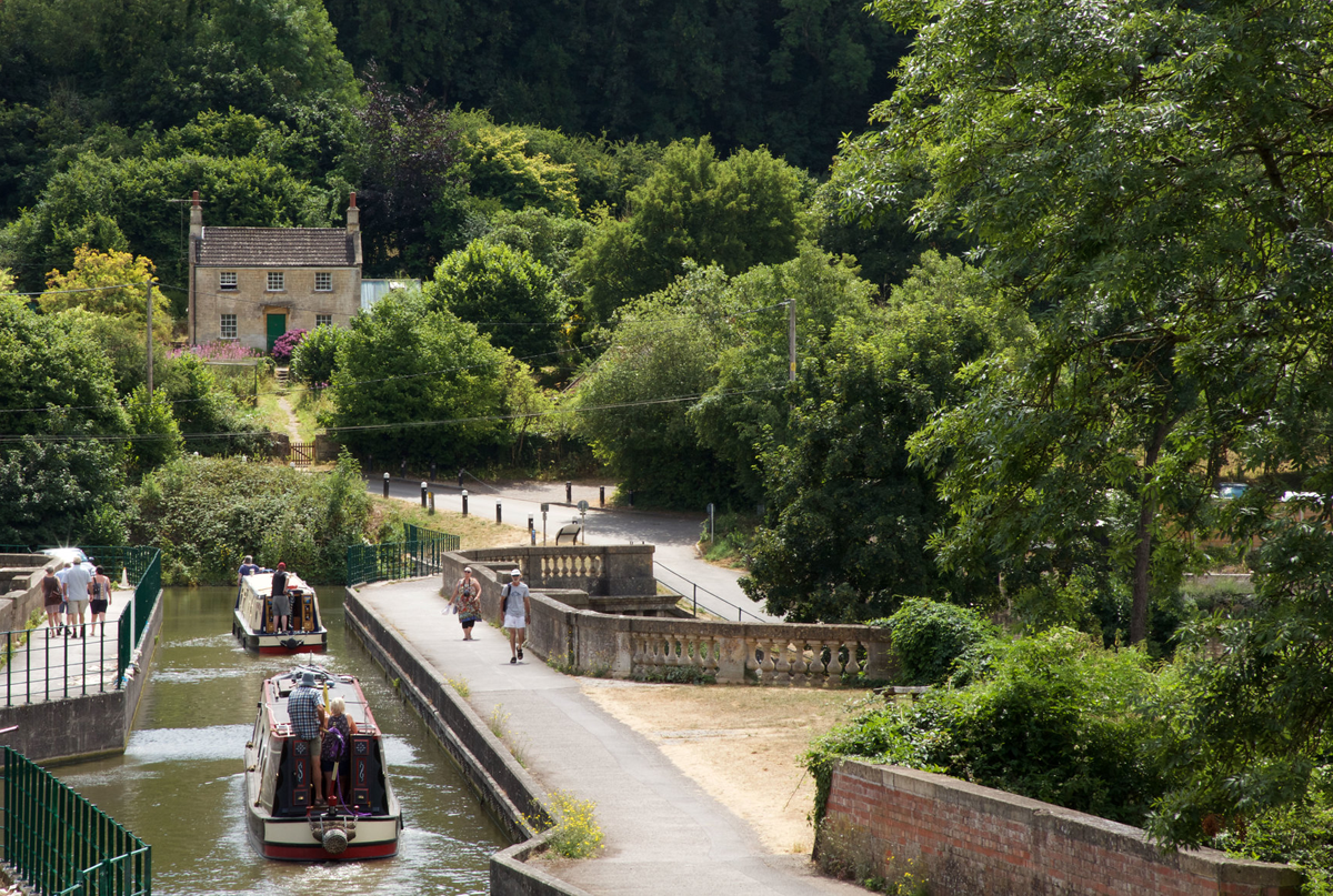 cottage overlooking canal with people on towpath