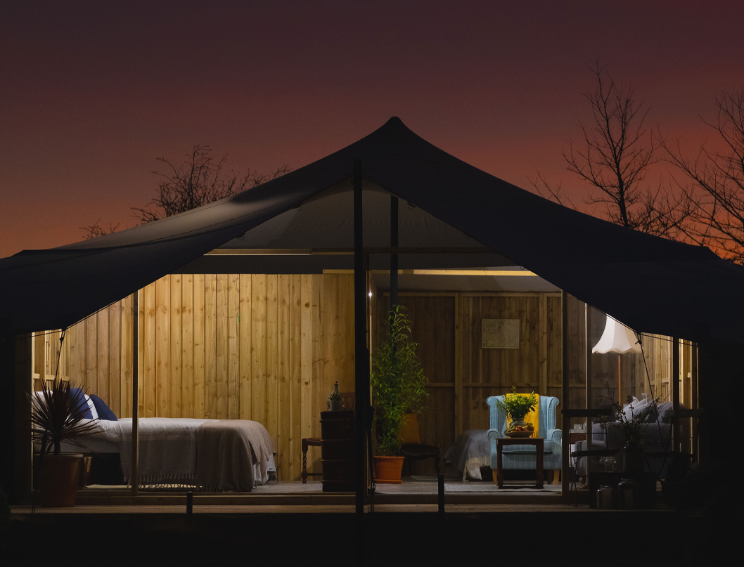 a glamping cabin lit up from within at night